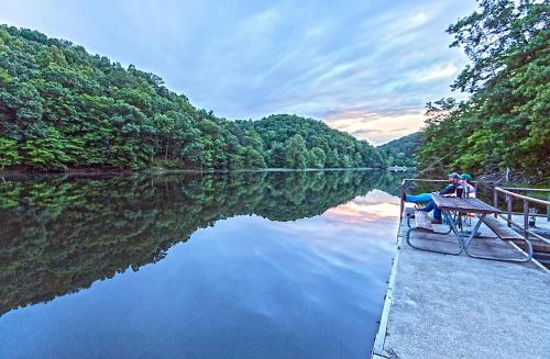 a man sitting on a bench on a boat on a river at Greenbo Lake State Resort Park in Argillite