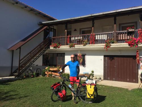a man standing next to a bike in front of a house at Kitka Hostel - Guest House in Tetovo