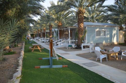 a row of tables and chairs in front of a house at Shkutai Hottub Arava in Ẕofar