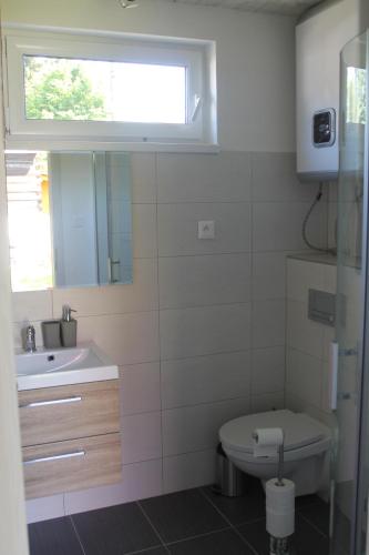 a bathroom with a toilet and a sink and a window at Malina - AND Apartment in Liptovský Mikuláš