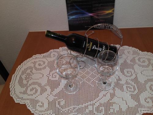 a bottle of wine sitting on a table with two wine glasses at Apartments Sandra in Tivat