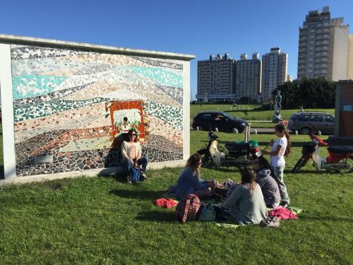 a group of people sitting in the grass in front of a wall at CABAÑA ÚNICA in Miramar