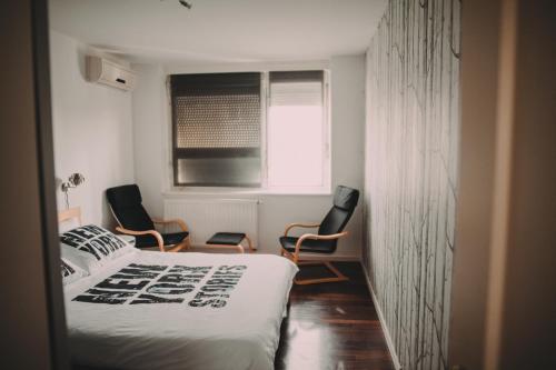 a bedroom with two chairs and a bed and a window at Globetrotter in Zagreb