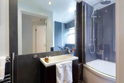 a bathroom with a sink and a shower and a tub at Primrose Boutique Home in London