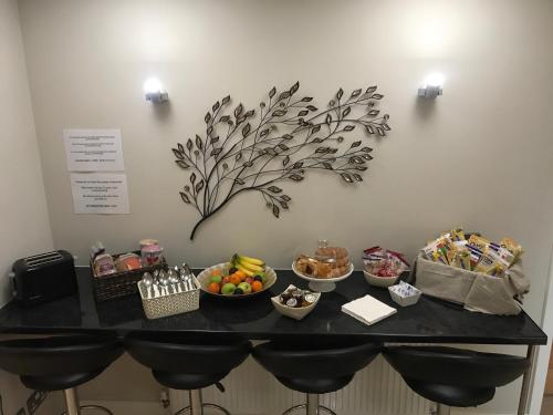 a table with snacks and fruits on it with a tree on the wall at Spire View at THE GALLEON RESTAURANT in Chesterfield