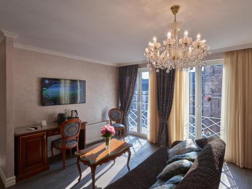 a living room with a chandelier and a table and a desk at Apartment-Hotel am Rathaus in Düsseldorf