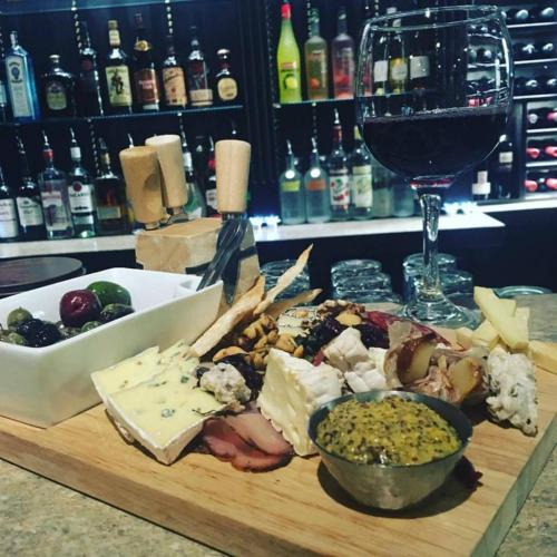 a wooden cutting board with cheese and a glass of wine at The Bulldog Hotel in Silver Star