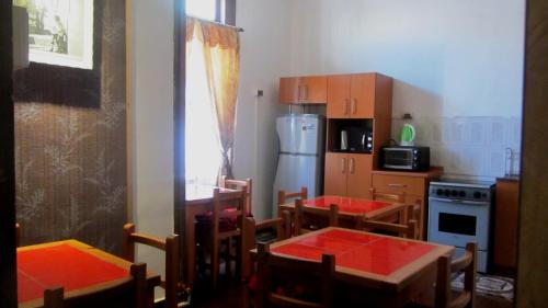 cocina con mesas, sillas y nevera en Hostal Odeón, en Valparaíso