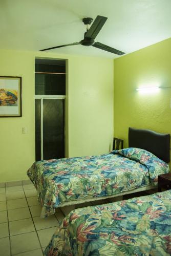 a bedroom with two beds and a ceiling fan at Hotel Esperanza in Mazatlán
