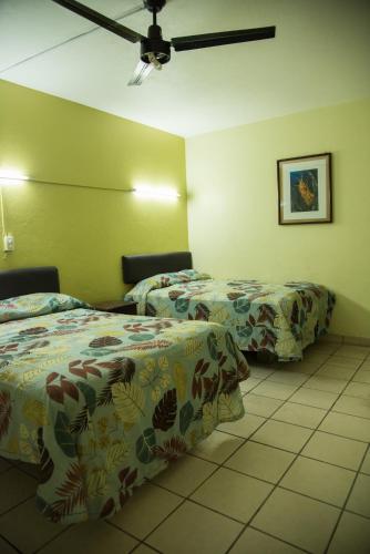 a hotel room with two beds and a ceiling fan at Hotel Esperanza in Mazatlán