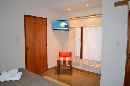 a bedroom with a red chair and a television on the wall at Al Sereno Hotel Panoramico in Tilcara