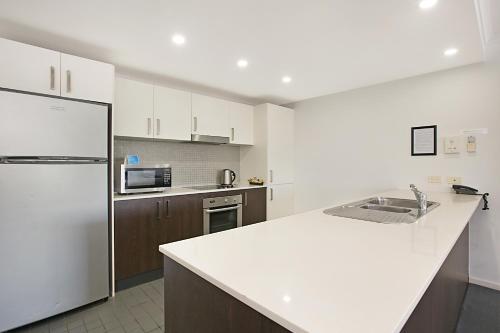 a kitchen with a white counter top and a refrigerator at Mantra Nelson Bay in Nelson Bay