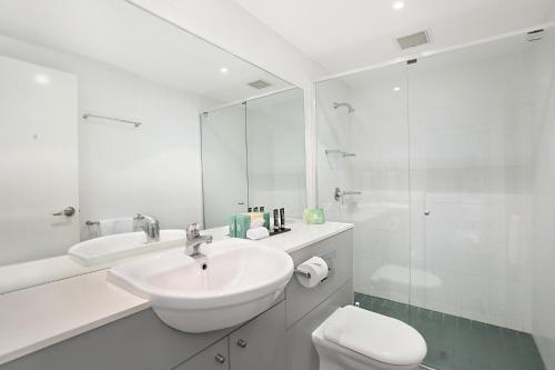 a white bathroom with a sink and a toilet at Mantra Nelson Bay in Nelson Bay