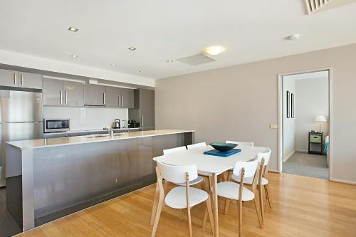 a kitchen and dining room with a white table and chairs at Mantra Nelson Bay in Nelson Bay