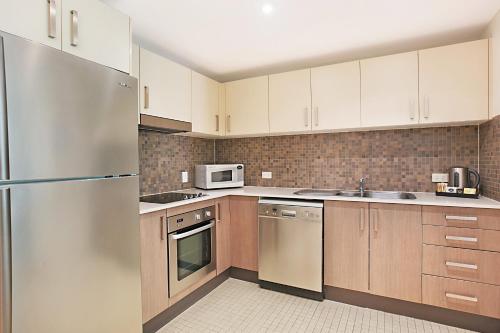 a kitchen with wooden cabinets and a stainless steel refrigerator at Mantra Nelson Bay in Nelson Bay
