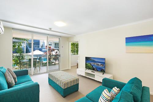 a living room with two blue couches and a tv at Mantra Nelson Bay in Nelson Bay