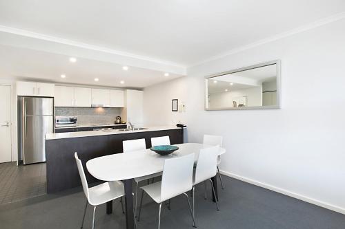 a kitchen and dining room with a white table and chairs at Mantra Nelson Bay in Nelson Bay