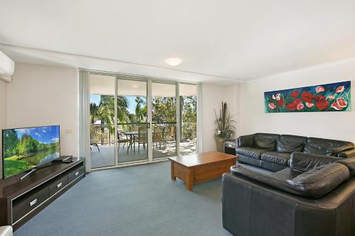a living room with a leather couch and a television at Mantra Nelson Bay in Nelson Bay