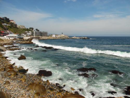 a beach with waves crashing on the rocks at Hostal Tunquelen in Valparaíso