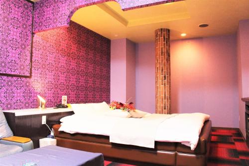 1 dormitorio con cama y pared púrpura en Pal Annex Yamaguchi (Love Hotel), en Iwakuni