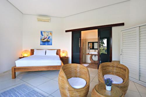 Villa Kipas Retreat في سينغيغي: غرفة نوم مع سرير وكرسيين الخوص