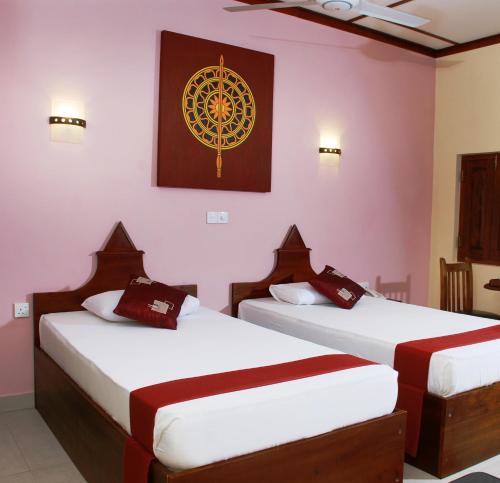 twee bedden in een kamer met een schilderij aan de muur bij The Triangle Hotel in Anuradhapura