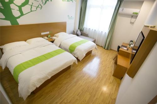 a hotel room with two beds and a television at Vatica AnHui Fuyang Linquan South Jiefang Hotel. in Linquan