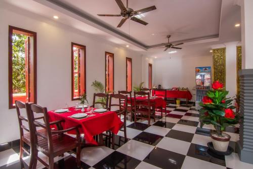 a restaurant with red tables and chairs on a checkered floor at Bou Savy Villa in Siem Reap