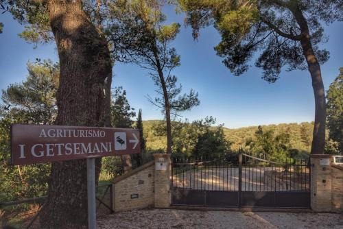 un cartello davanti a un cancello con un albero di Agriturismo I Getsemani a Bevagna