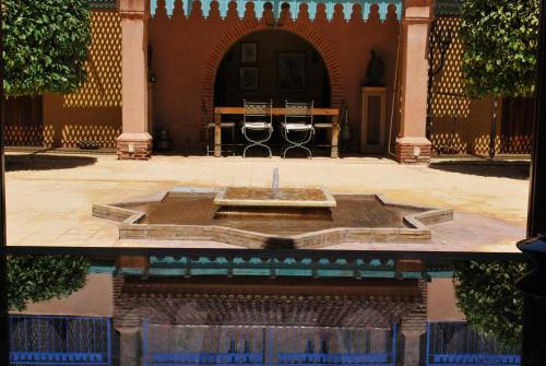 a pool of water in front of a building with a fountain at Casa Taos in Marrakech