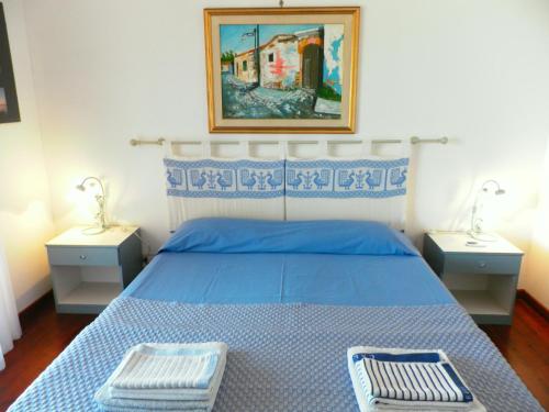 um quarto com uma cama azul com duas mesas de cabeceira em Ajò Faci a Mari em Capoterra