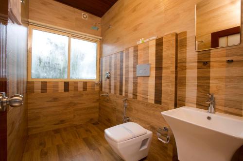a bathroom with a white sink and a toilet at Dream Catcher Plantation Resort in Munnar