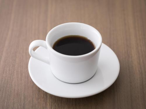 a cup of coffee sitting on a plate on a table at Hotel Wing International Hakata Shinkansenguchi in Fukuoka