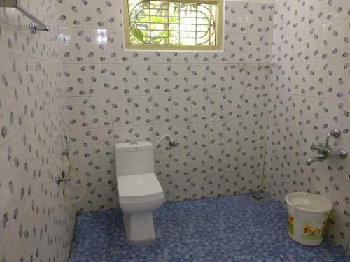 a bathroom with a toilet and a window at The Shades Holiday inn in Kushālnagar