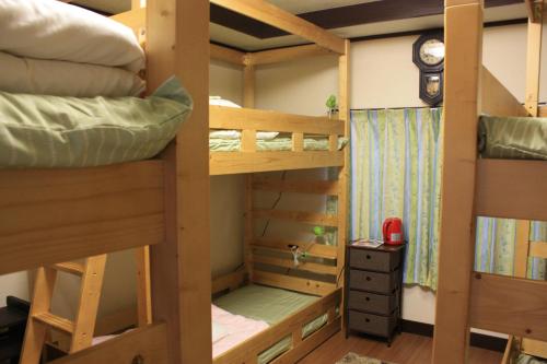 2 łóżka piętrowe w pokoju z zegarem w obiekcie Guesthouse Seiryu Kibako w mieście Ome