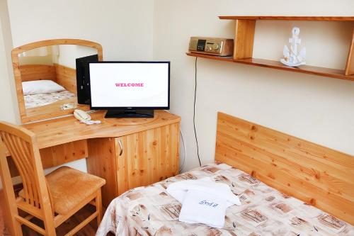 a bedroom with a bed and a desk with a television at Ośrodek Wypoczynkowy Gryf II in Kołobrzeg