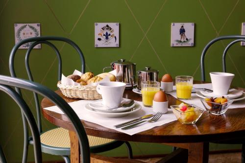 a wooden table with breakfast foods and orange juice at Grand Hotel de L'Univers in Amiens