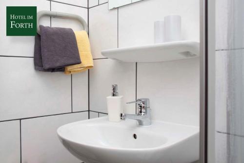 ein weißes Bad mit einem Waschbecken und einem WC in der Unterkunft Hotel im Forth in Oyten