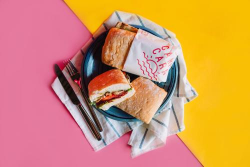 a plate with a sandwich on a colorful table at Cara Cara Inn in Kuta