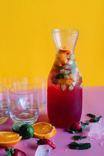 a drink in a vase with fruit on a table at Cara Cara Inn in Kuta
