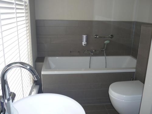 a bathroom with a bath tub and a toilet at In den Verdwaalde Koogel in Heusden