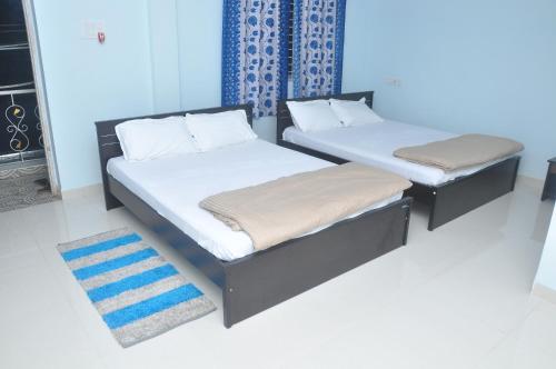 two twin beds in a room with a rug at SriPaadha Inn Kanipakam in Kanipakam