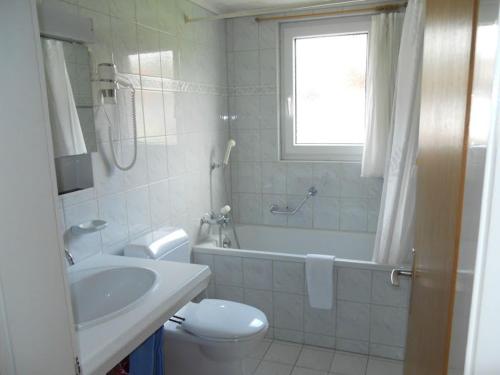 a bathroom with a toilet and a tub and a sink at Chalet Anemone 2 in Mürren