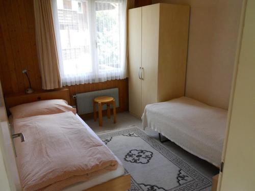 niewielka sypialnia z 2 łóżkami i oknem w obiekcie Chalet Anemone 2 w mieście Mürren