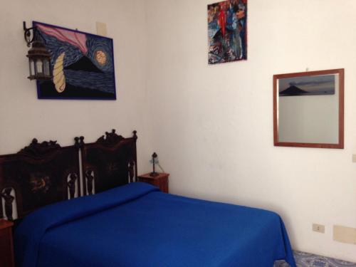 a bedroom with a blue bed and a mirror at La Lampara in Stromboli
