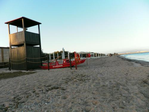 a beach with a lifeguard tower and a red boat at Ajò Faci a Mari in Capoterra