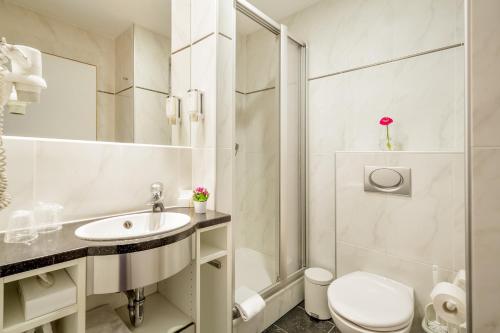 a bathroom with a toilet and a sink and a shower at MesseHotel Köln-Deutz in Cologne