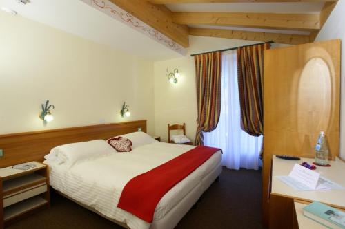 A bed or beds in a room at Hotel des Alpes
