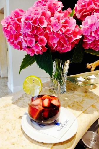a vase of pink flowers with a drink in a glass at JR Resort Logos Forte dei Marmi in Forte dei Marmi