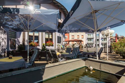 a pool of water with chairs and tables and umbrellas at Hotel Kasserolle in Siegburg